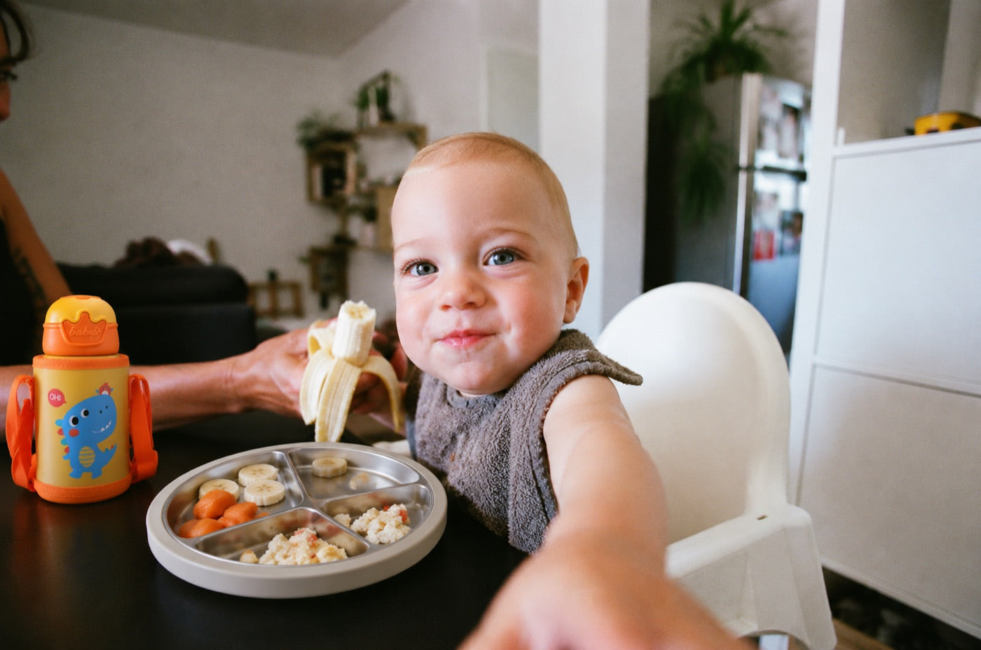 A toddler eating from a Little Plate next to a Tumble Bottle
